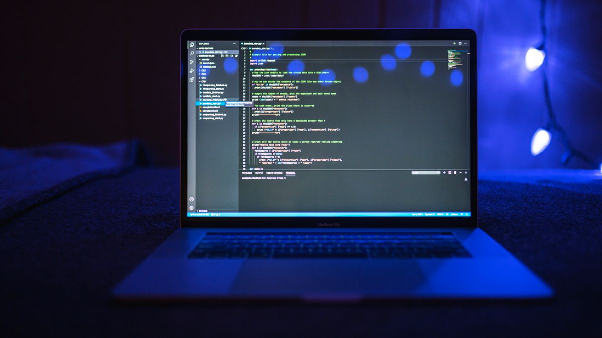 A laptop showing application code in a darkened room.